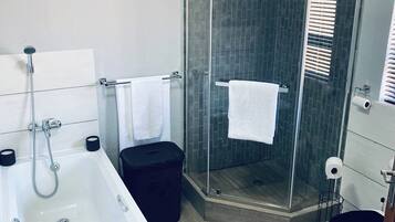 A modern bathroom with a bathtub, a glass-enclosed shower, and a toilet.