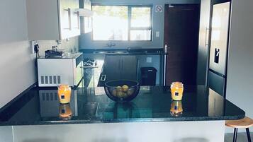 Een moderne keuken met een centraal eiland, barkrukken en een raam dat voor natuurlijk licht zorgt.