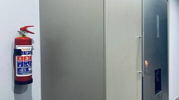 Un pasillo con un extintor de incendios en la pared y un refrigerador.