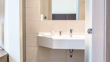 A modern bathroom with a white sink, mirror, and shower.