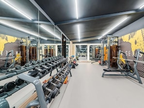 A gym with mirrored walls, various exercise equipment, and a clean, modern design. - Atour Hotel (Zibo)