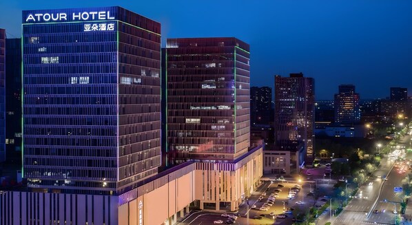 Een modern hotelgebouw met een opvallend bord, meerdere verdiepingen en een parkeerplaats op de voorgrond.