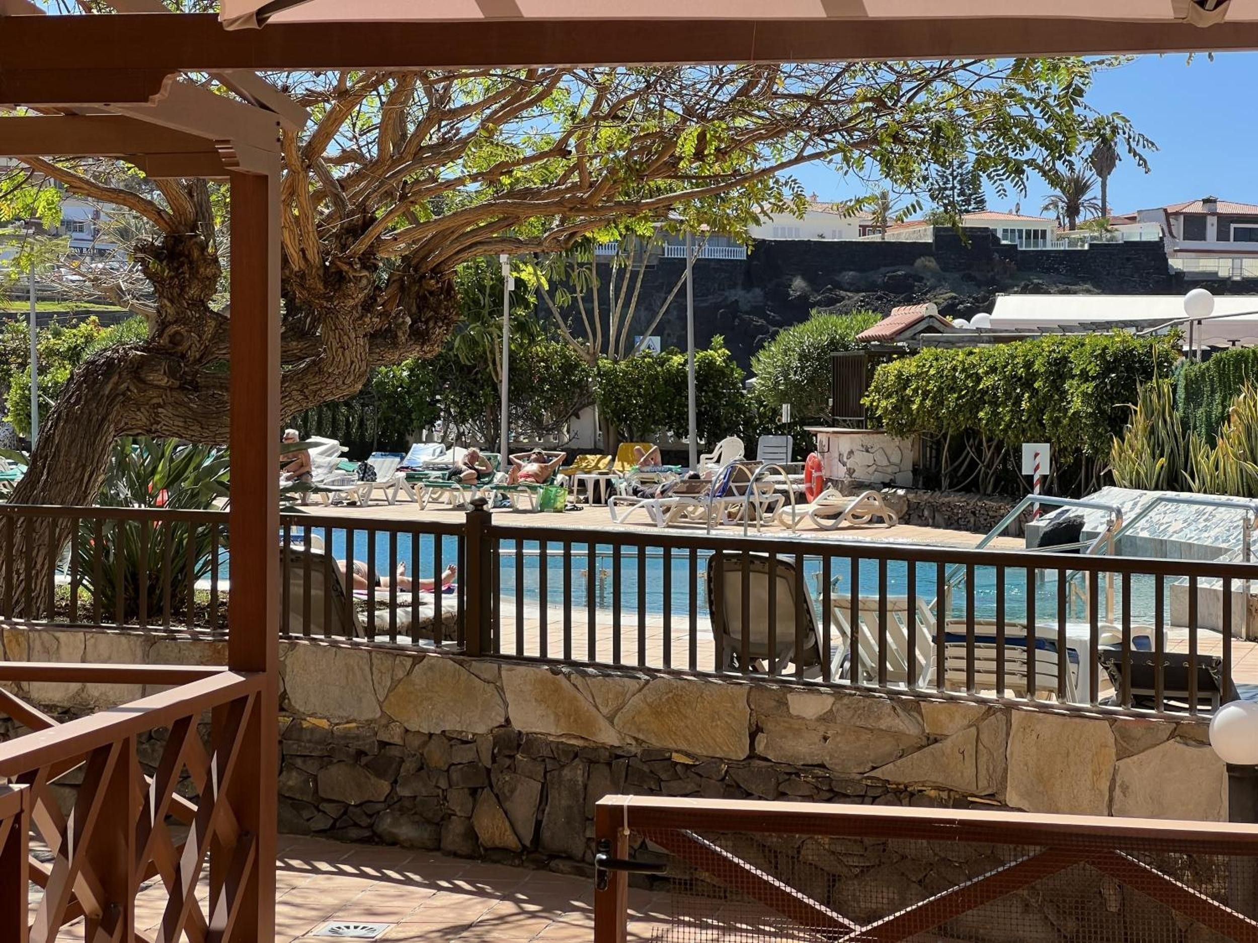 A pool area with lounge chairs and a stone wall.