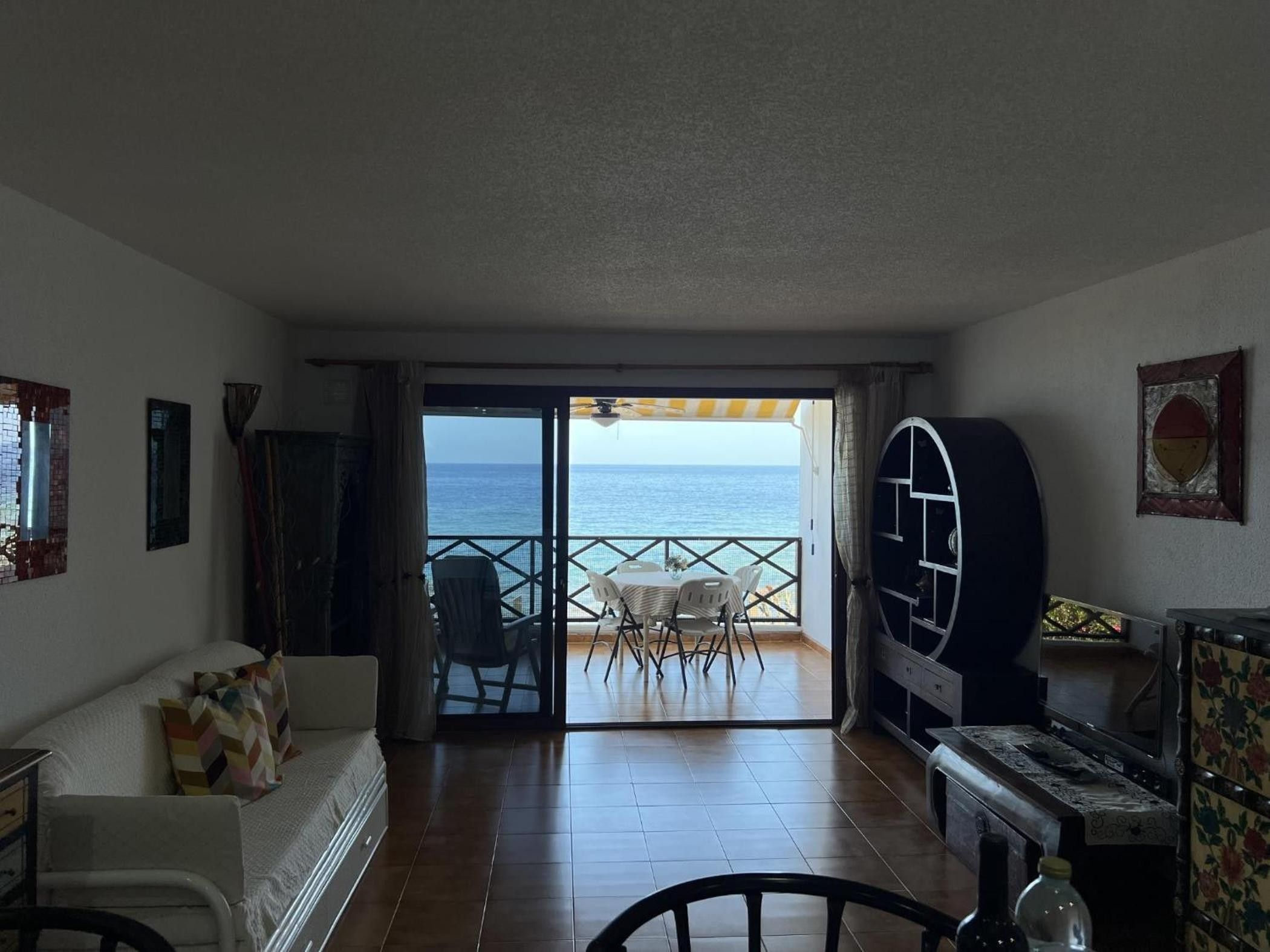 Una habitación con vista al mar, un comedor con sillas, un sofá y un televisor.