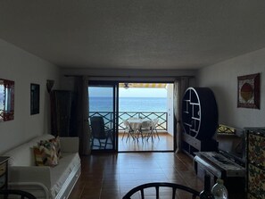 Una habitación con vista al mar, un comedor con sillas, un sofá y un televisor.