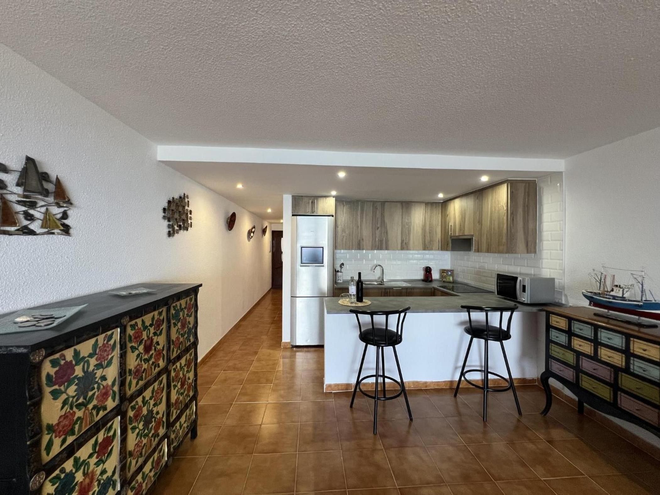 Eine moderne Küche mit einer zentralen Kochinsel, Barhocker und einem dekorativen Schrank.