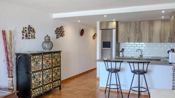 Una cocina moderna con una isla central, taburetes de bar y un mueble decorativo.