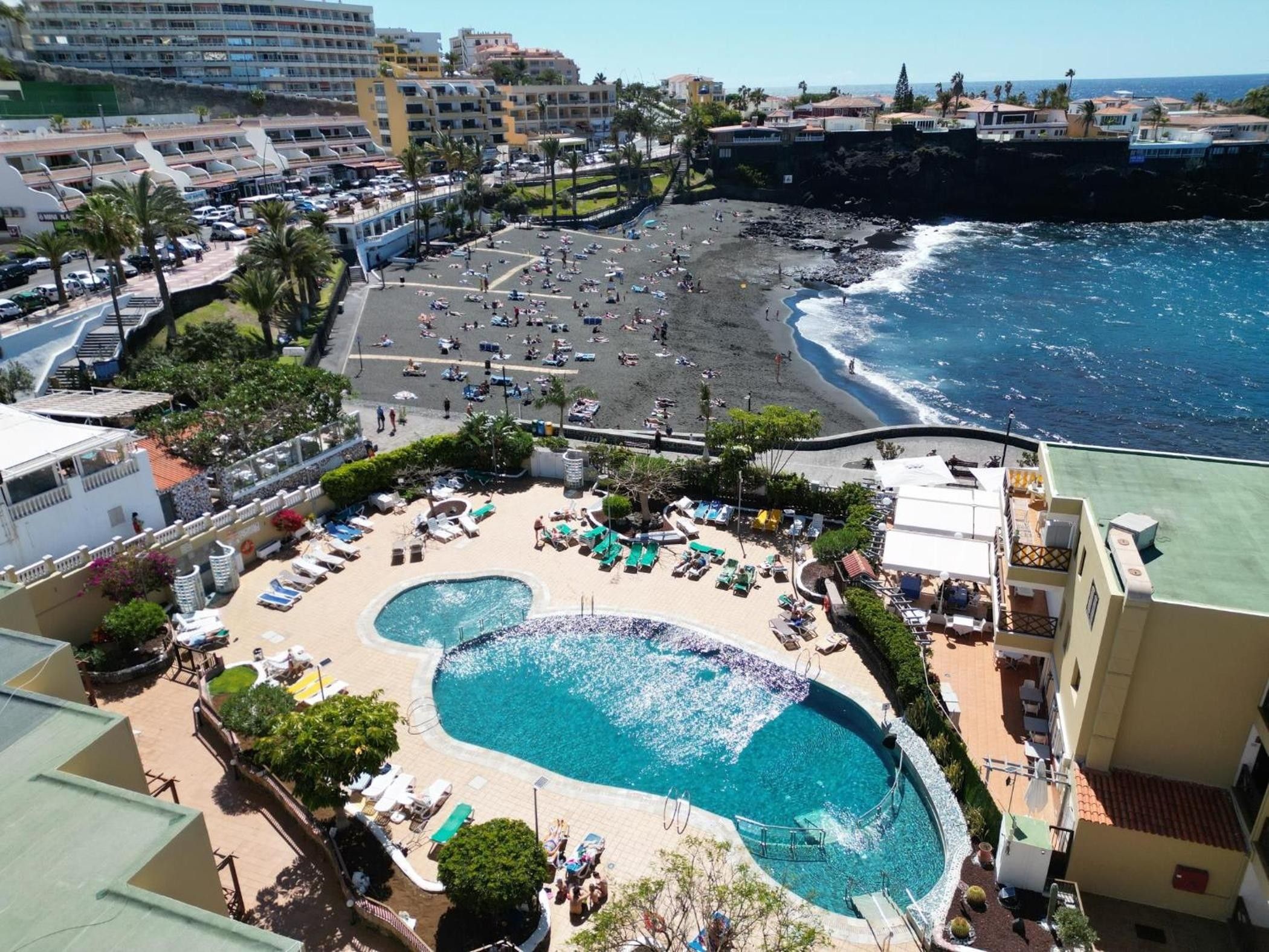 Un resort con piscina central, acceso a la playa y vistas al océano.