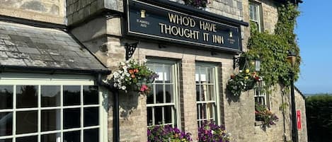 Un edificio de piedra con un letrero que dice 'WHOD HAVE THOUGHT IT INN' y 'S. AUSTELL ALES'.
