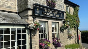 Un edificio de piedra con un letrero que dice 'WHOD HAVE THOUGHT IT INN' y 'S. AUSTELL ALES'.