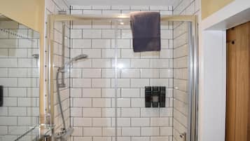 A glass-enclosed shower with a towel hanging on the door handle.