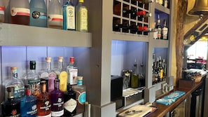 Zona de bar con diversas botellas de licor y una estantería para vinos.