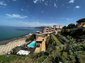 Una propiedad frente al mar con piscina, sombrillas de playa y vistas al océano.