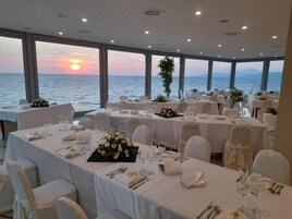 A dining area with tables set for a meal, overlooking a body of water.