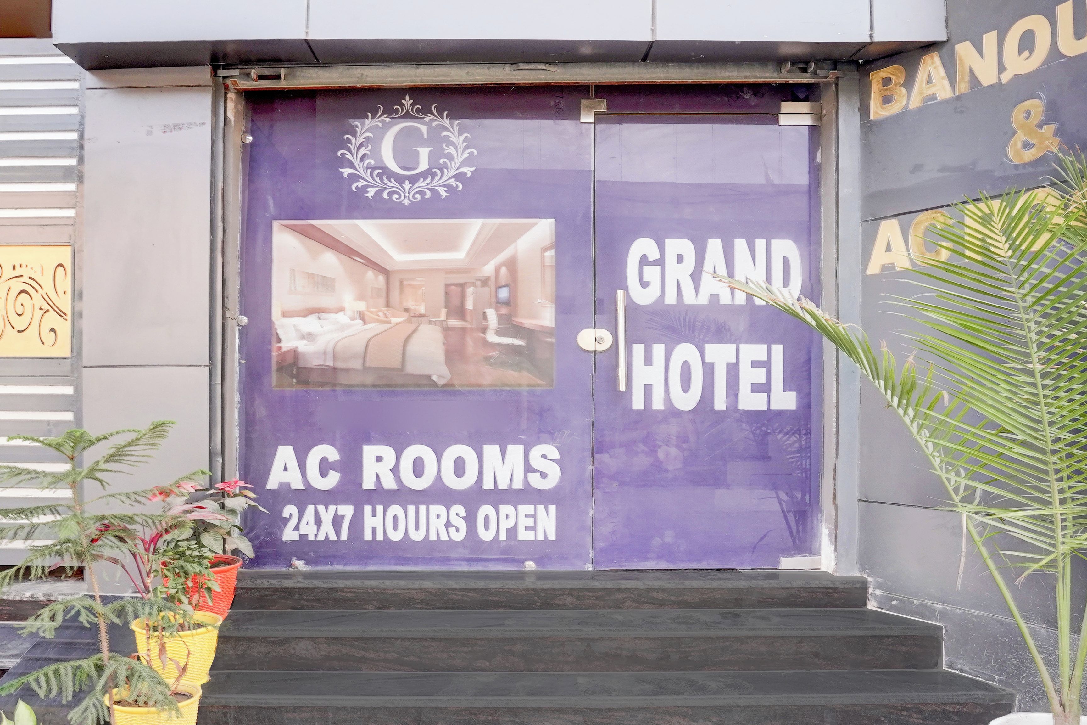 Entrada de hotel com placa indicando 'AC ROOMS 24X7 HOURS OPEN'.