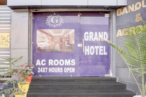 Entrada de hotel com placa indicando 'AC ROOMS 24X7 HOURS OPEN'.