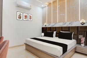 A modern bedroom with a large bed, a nightstand, a lamp, and a wall-mounted air conditioner.
