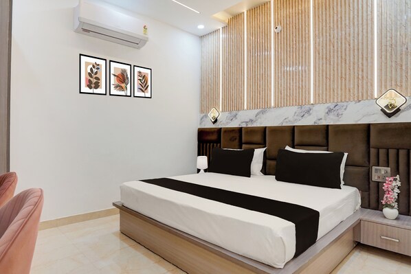 A modern bedroom with a large bed, a nightstand, a lamp, and a wall-mounted air conditioner.