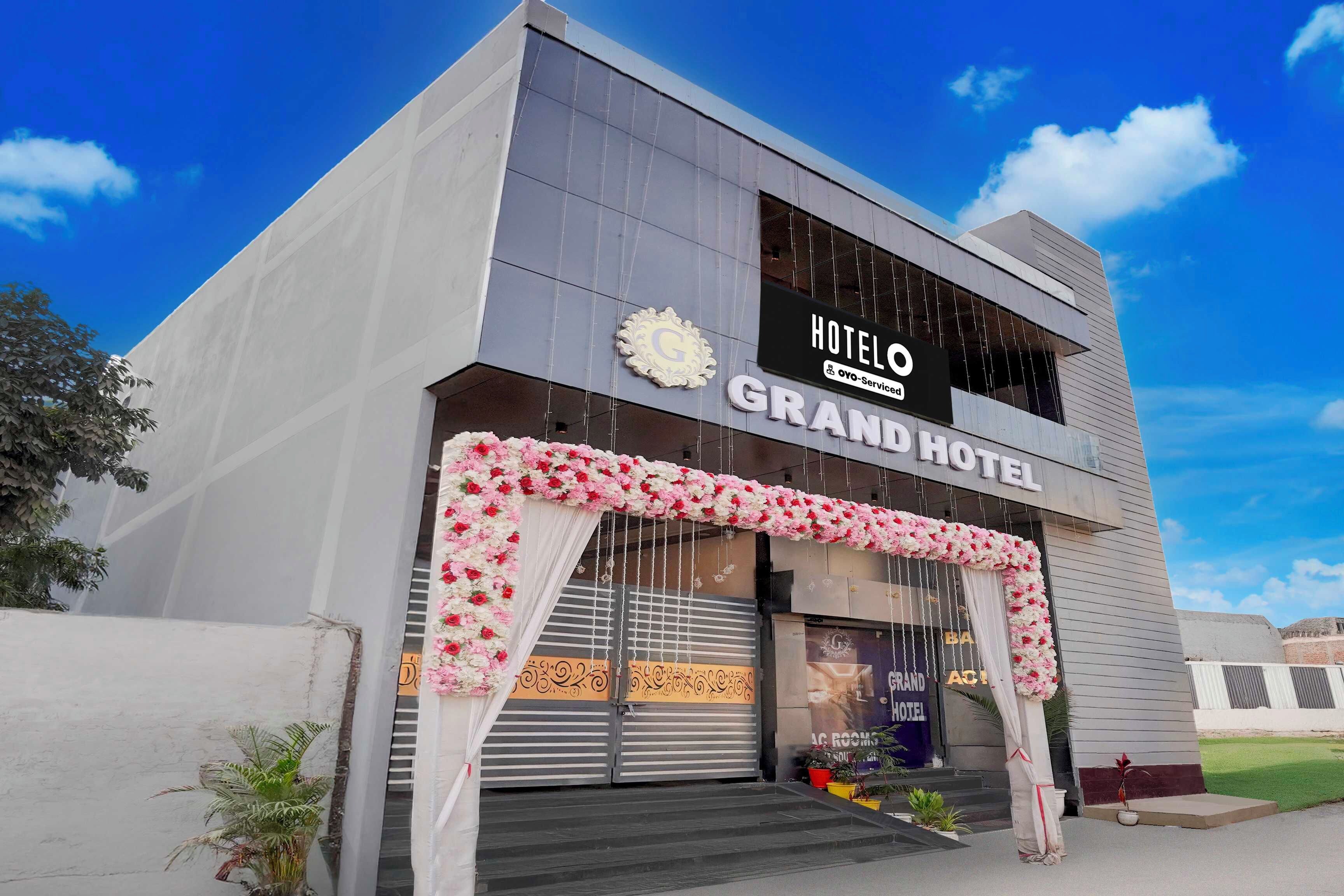 Un hotel con una doble fachada, un letrero llamativo y un arco de flores decorativo en la entrada.