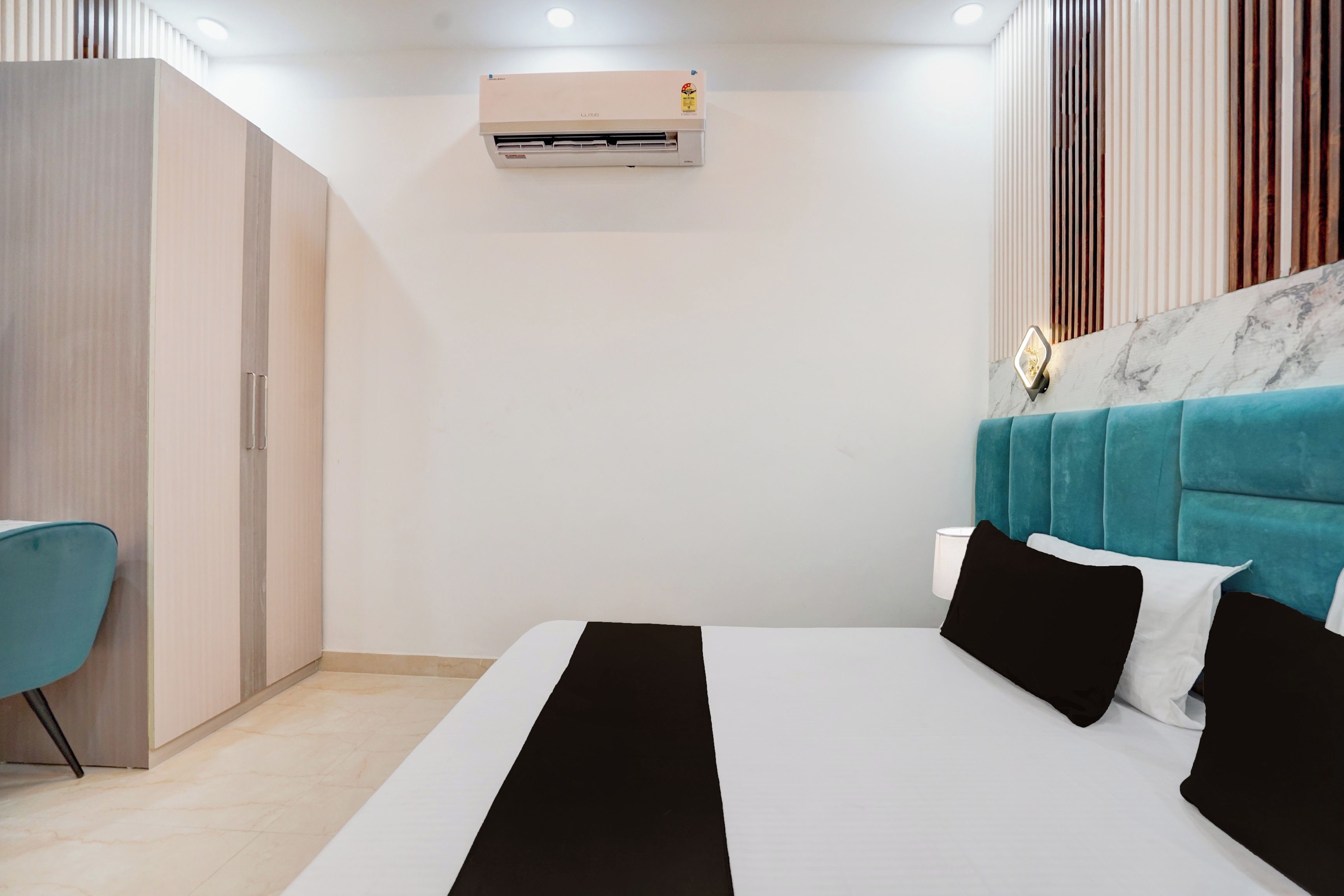 Quarto de hotel moderno com cama, escrivaninha, guarda-roupa e ar condicionado.