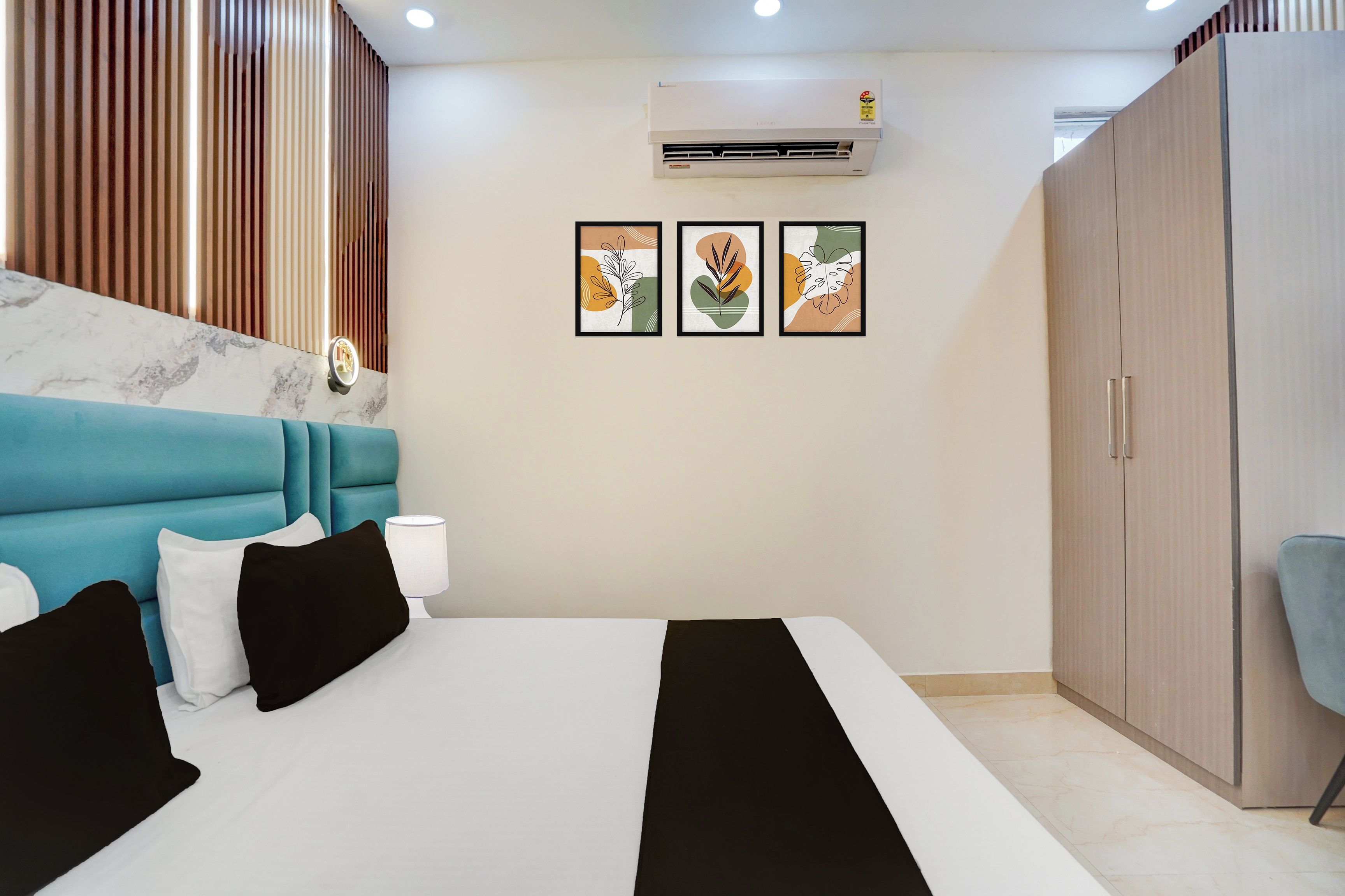 Un dormitorio con cama, armario, escritorio y silla. Hay tres cuadros enmarcados en la pared.