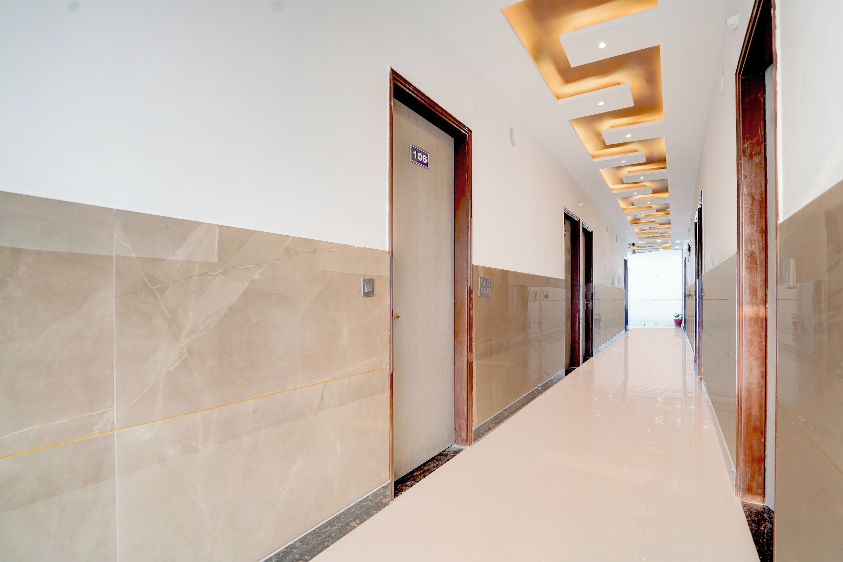 Un pasillo moderno con paredes de mármol y suelo brillante, que conduce a una habitación luminosa.
