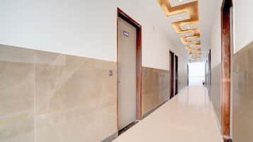 Un pasillo moderno con paredes de mármol y suelo brillante, que conduce a una habitación luminosa.