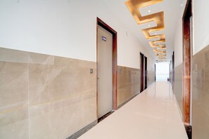 Corredor moderno com paredes de mármore e piso brilhante, que leva a um ambiente claro.
