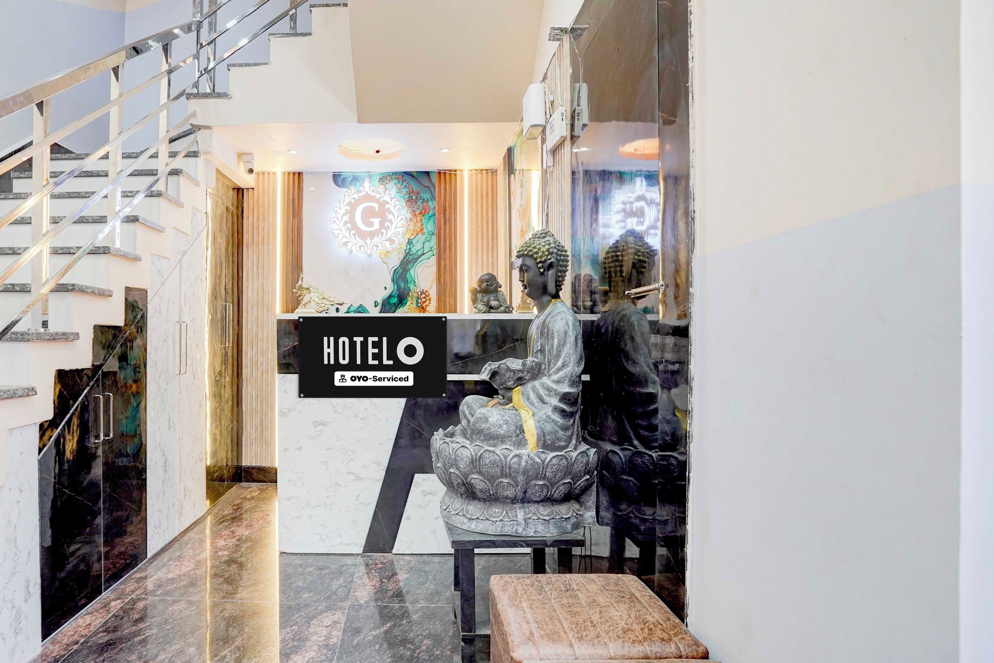 Zona de recepción de hotel con una escalera moderna, un mostrador de recepción y una estatua de Buda.