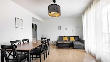 Un espacio de estar moderno con comedor, un sofá con cojines e iluminación colgante.