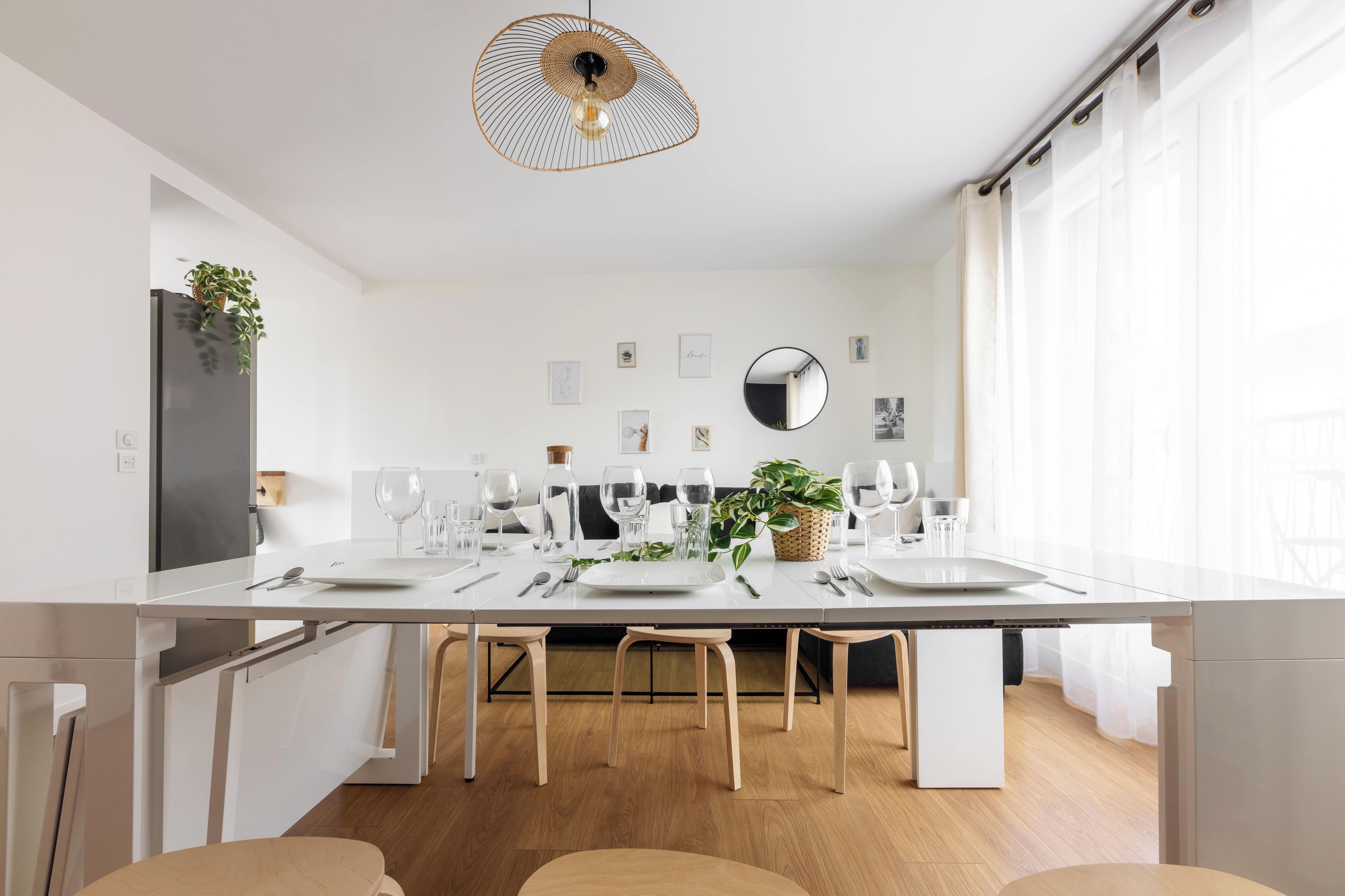 Een moderne eetruimte met een lange tafel voor vier personen, omringd door stoelen, met een hanglamp erboven.