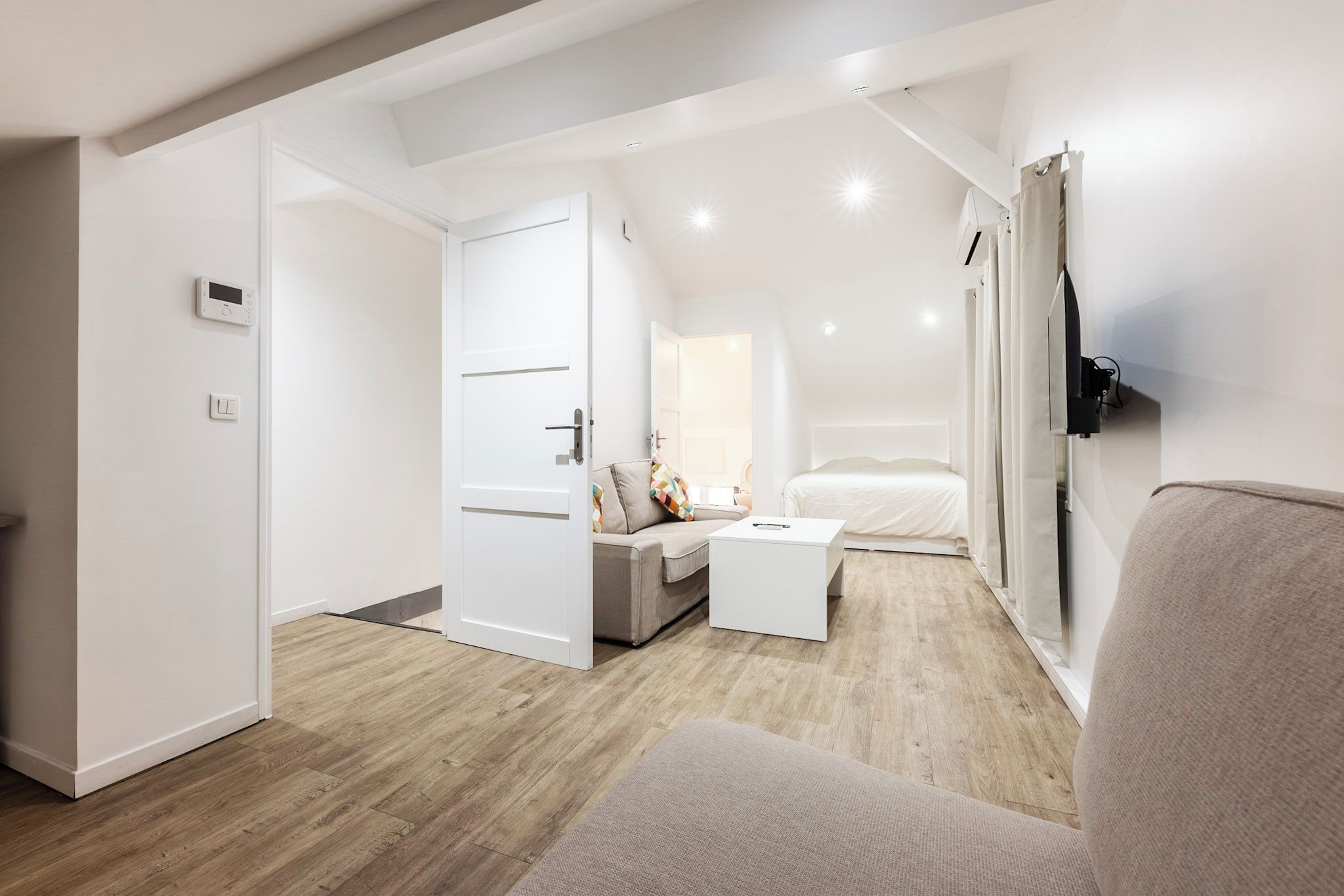 Un dormitorio moderno con cama, mesita de noche y televisor montado en la pared.
