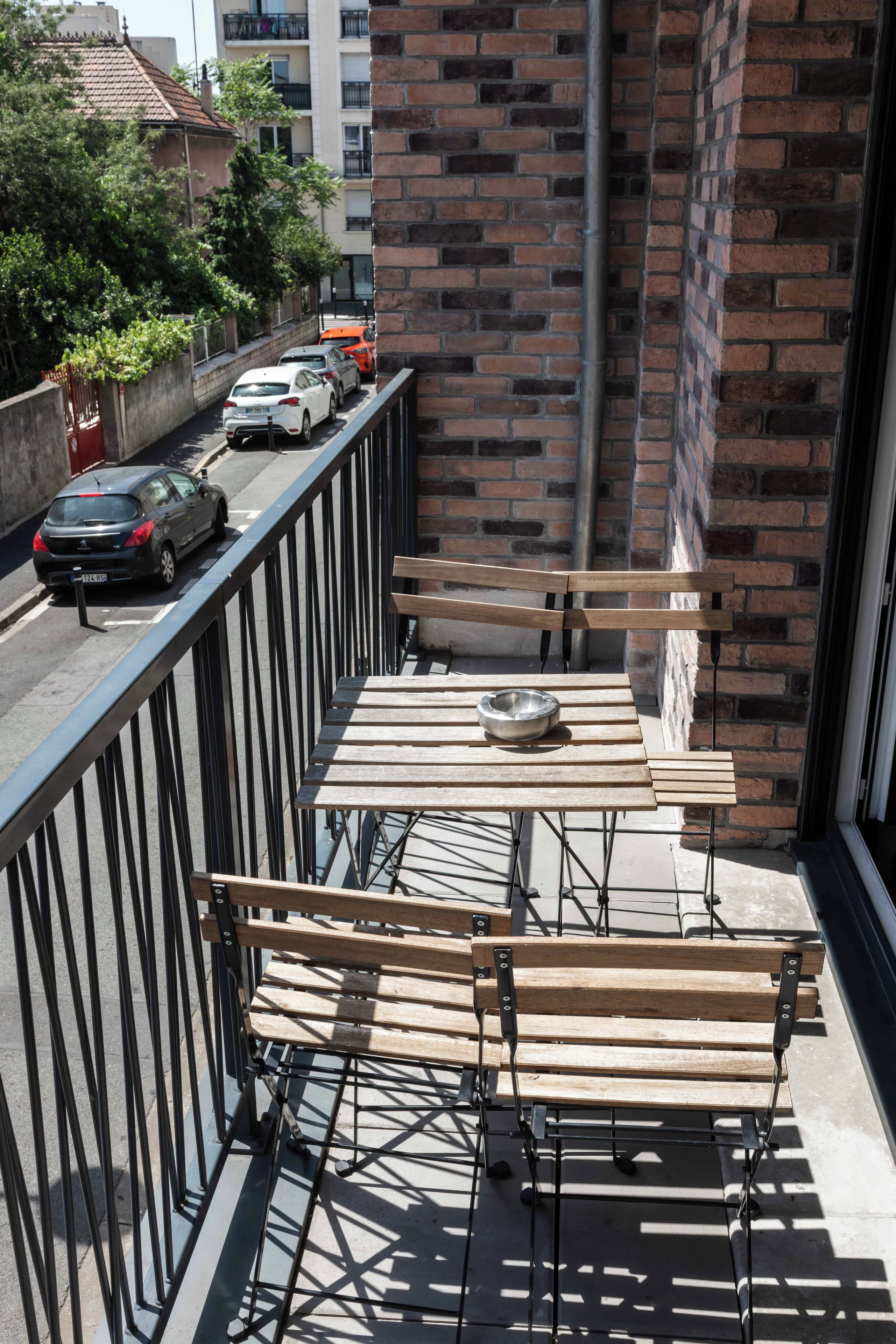 A balcony with a metal railing, a wooden table, and a bench.