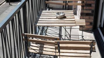 A balcony with a metal railing, a wooden table, and a bench.
