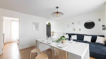 Una cocina moderna con una mesa de comedor para cuatro personas, un sofá oscuro y una lámpara colgante.