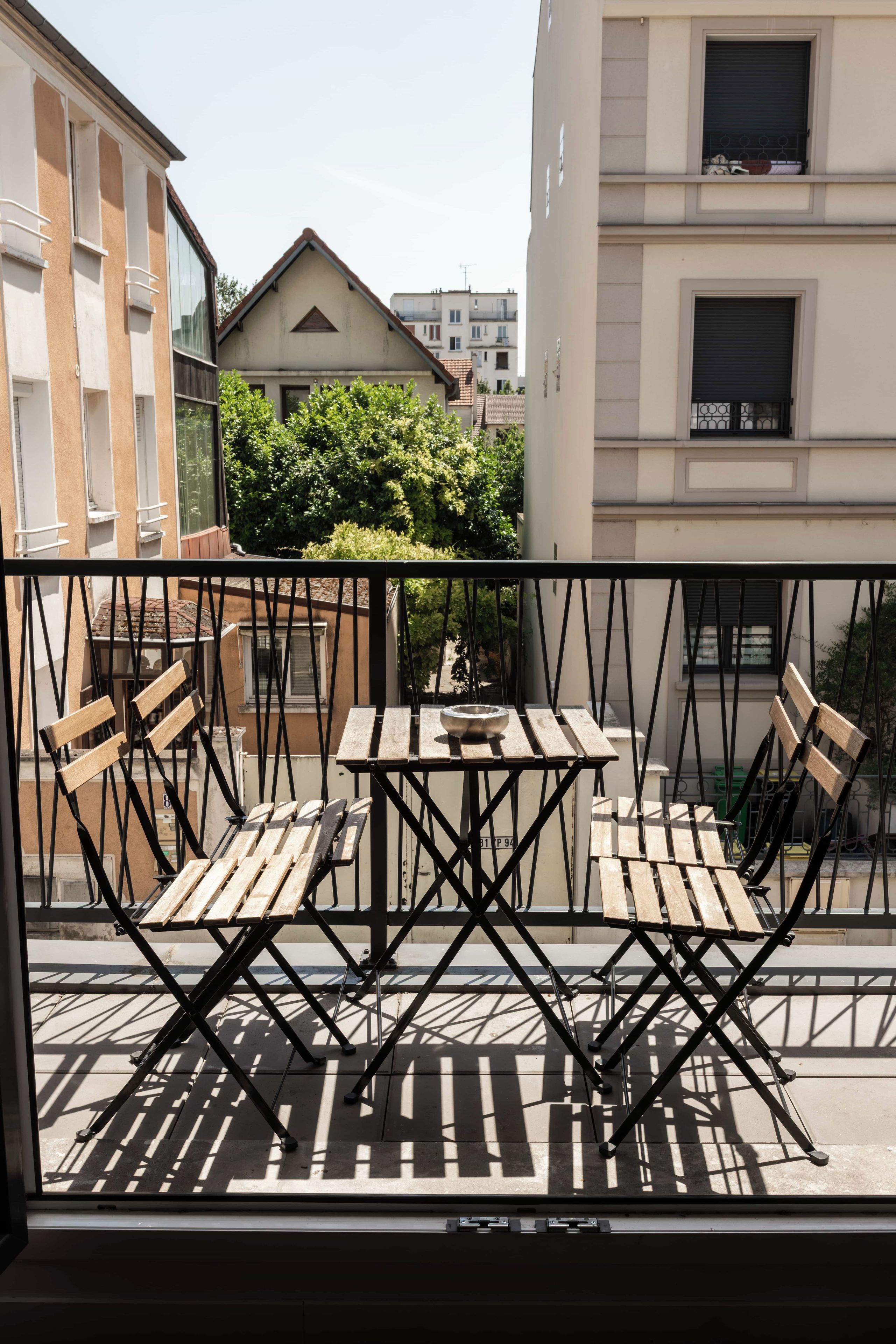 Un balcón con mesa y sillas, con vistas a una zona residencial con edificios y zonas verdes.