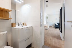 Un baño moderno con lavamanos blanco, tocador de madera y espejo.