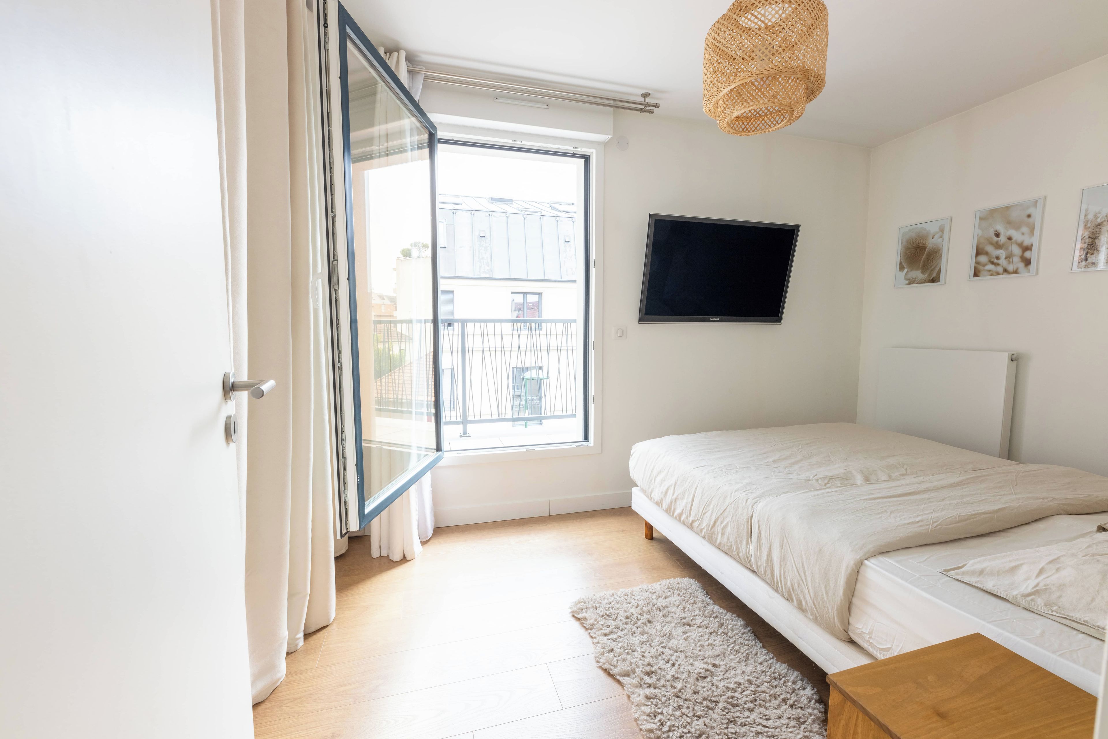 Een slaapkamer met een bed, een televisie en een raam met gordijnen.