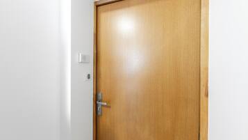 Una puerta de madera con un picaporte plateado y una pared blanca.