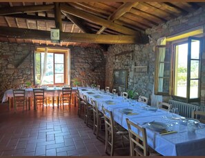 A dining area with stone walls, wooden beams, and a long table set for a meal. - DIMORA ORTENSIA—A GLEAM INTO NATURE AND TUSCAN RELAXATION (Lucolena In Chianti)