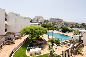 A pool area with lounge chairs, a tree, and a view of surrounding buildings. - Apartment 'Neptuno Ocean Experience By Sydney' with Sea View, Shared Pool and Wi-Fi (La Arena)