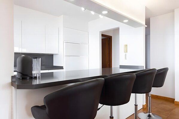 A modern kitchen with a central island, bar stools, and a view into the adjacent dining area. - Apartment 'Neptuno Ocean Experience By Sydney' with Sea View, Shared Pool and Wi-Fi (La Arena)