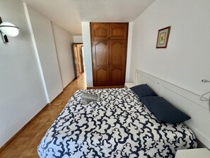 A bedroom with a bed, a nightstand, a wooden wardrobe, and a framed picture on the wall. - Apartment 'Neptuno Ocean Experience By Sydney' with Sea View, Shared Pool and Wi-Fi (La Arena)
