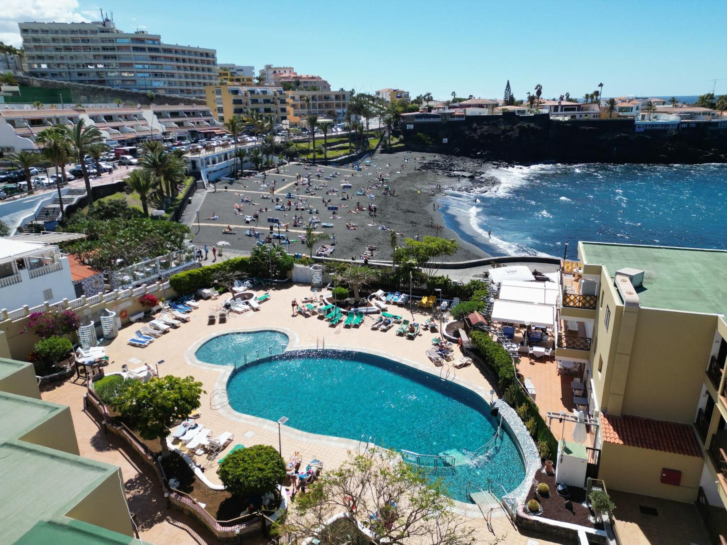 A resort with a large pool, a beach, and a view of the ocean.
