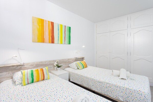 A hotel room with two beds, a white wardrobe, and a colorful abstract painting on the wall. - Vacation Apartment 'Playa De La Arena By Sydney' with Sea View, Shared Pool and Wi-Fi (Santa Cruz de Tenerife)