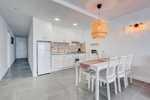 A modern kitchen with white cabinets, a dining table with chairs, and a hanging light fixture. - Vacation Apartment 'Neptuno 2a017' with Sea View, Shared Pool and Wi-Fi (Santa Cruz de Tenerife)