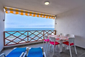 A balcony with a view of the sea, a table with chairs, and two sun loungers. - Vacation Apartment 'Neptuno 2a017' with Sea View, Shared Pool and Wi-Fi (Santa Cruz de Tenerife)