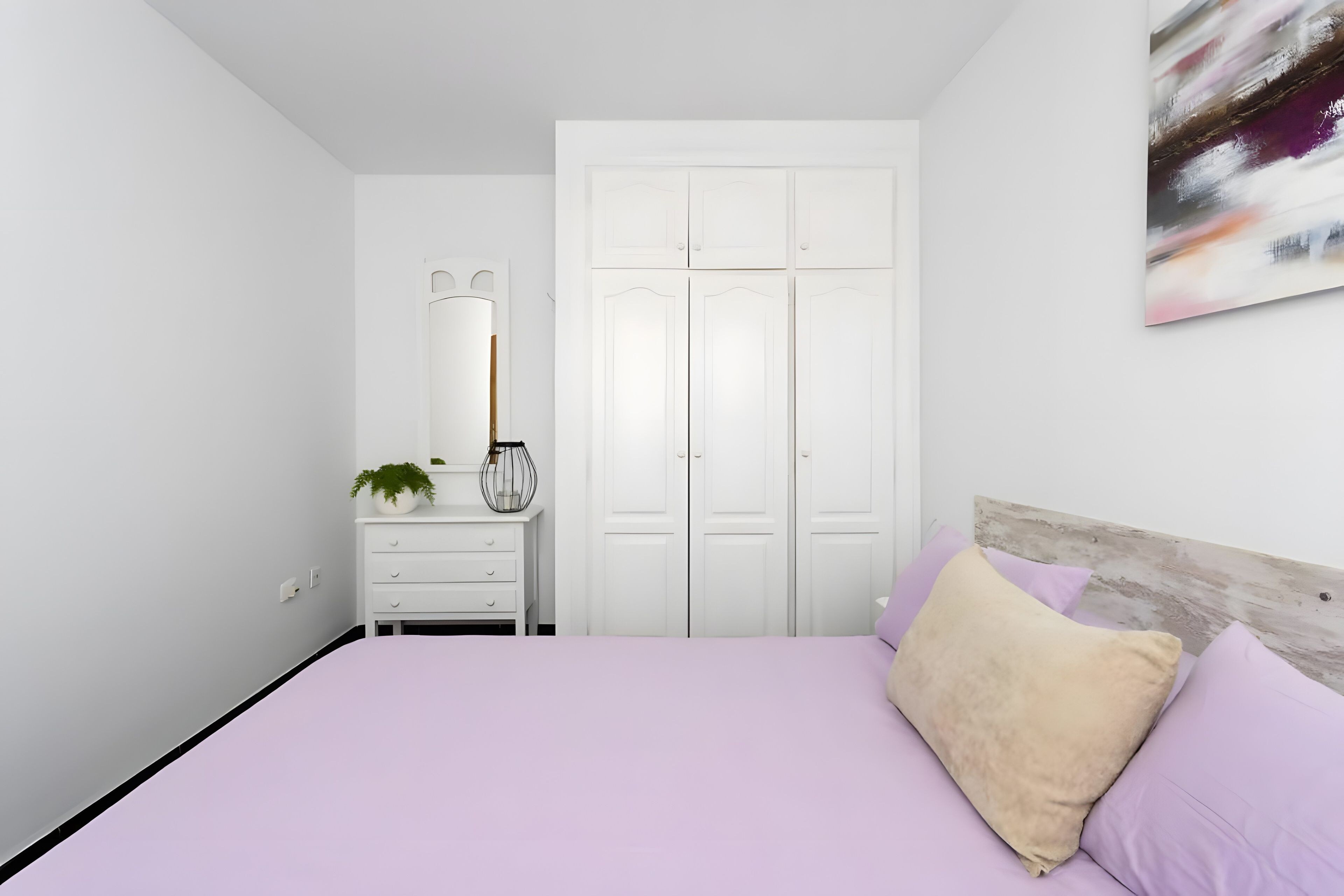 Une chambre à coucher avec un lit, une commode, un miroir et une armoire.