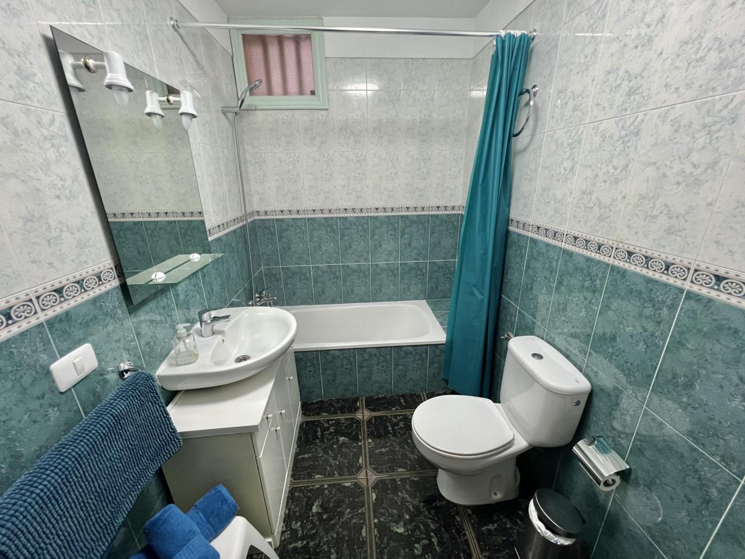 Een badkamer met een bad, toilet, wastafel en een douchegordijn.
