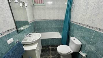 Een badkamer met een bad, toilet, wastafel en een douchegordijn.
